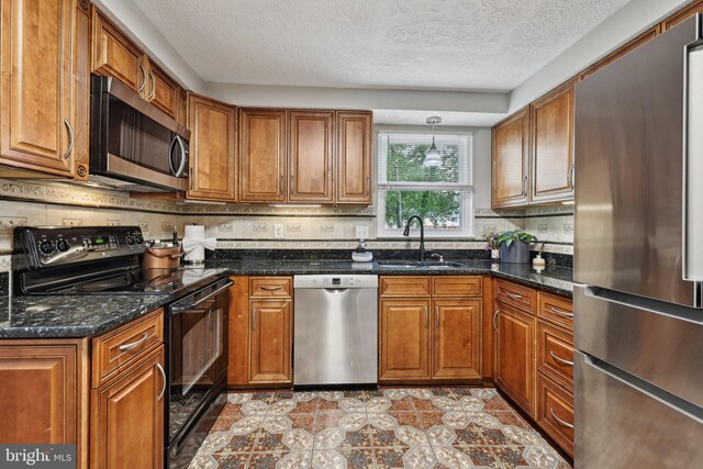 7112 Bonniemill Ln, Springfield, VA 22150 - kitchen featuring stainless steel appliances, a sink, brown cabinetry, a textured ceiling, and dark stone counters