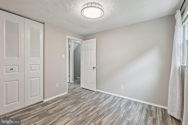 7112 Bonniemill Ln, Springfield, VA 22150 - unfurnished bedroom featuring wood finished floors, baseboards, a closet, and a textured ceiling