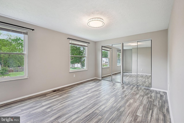 7112 Bonniemill Ln, Springfield, VA 22150 - unfurnished bedroom with wood finished floors, multiple closets, a textured ceiling, and baseboards
