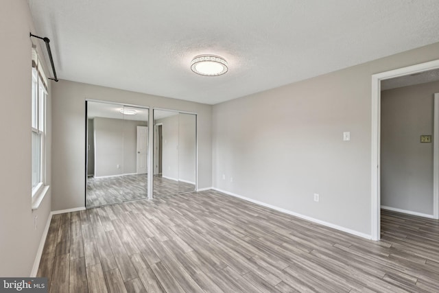 7112 Bonniemill Ln, Springfield, VA 22150 - unfurnished bedroom featuring wood finished floors, baseboards, a textured ceiling, and multiple windows
