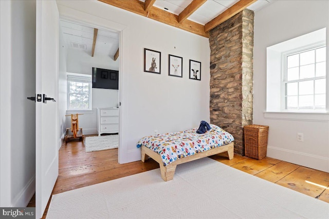 bedroom featuring hardwood / wood-style floors, baseboards, beamed ceiling, and visible vents