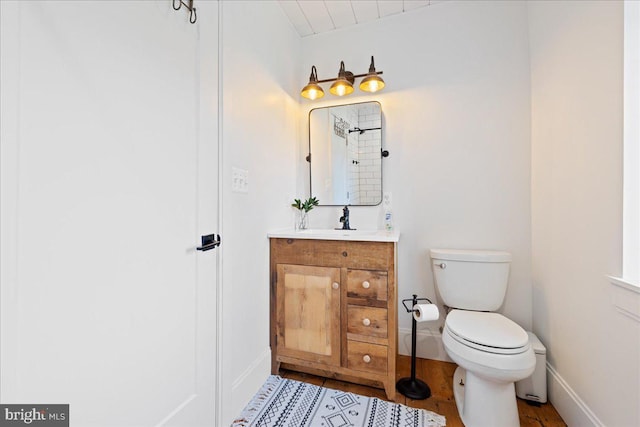 bathroom with toilet, wood finished floors, vanity, and baseboards