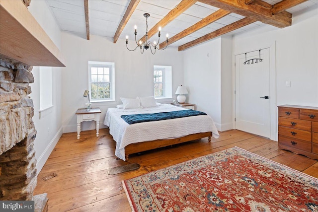 bedroom featuring beam ceiling, light wood-style floors, a notable chandelier, and baseboards