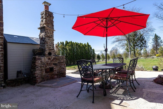 view of patio featuring outdoor dining space and an outdoor stone fireplace