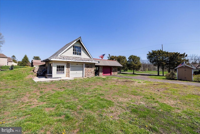 exterior space featuring a lawn, a storage shed, aphalt driveway, and an outbuilding