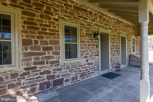 doorway to property featuring a porch and brick siding