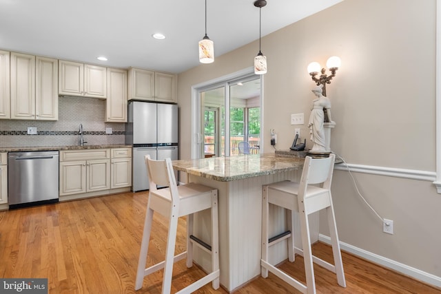 13709 Wendover Rd, Silver Spring, MD 20904 - kitchen featuring stainless steel appliances, cream cabinets, light wood-type flooring, a breakfast bar, and a sink