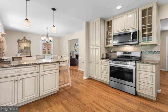 13709 Wendover Rd, Silver Spring, MD 20904 - kitchen featuring appliances with stainless steel finishes, cream cabinetry, light wood-style flooring, a chandelier, and decorative backsplash