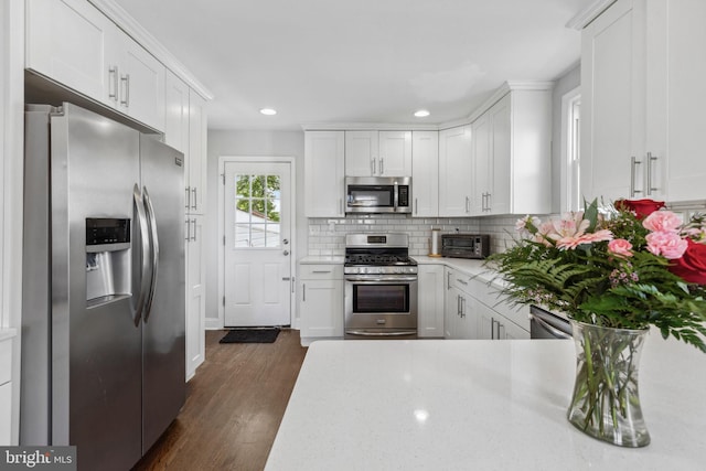 kitchen with stainless steel appliances, decorative backsplash, dark wood finished floors, white cabinetry, and recessed lighting