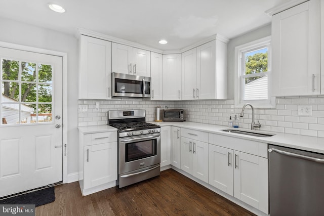 kitchen with stainless steel appliances, a sink, light countertops, dark wood-type flooring, and white cabinetry
