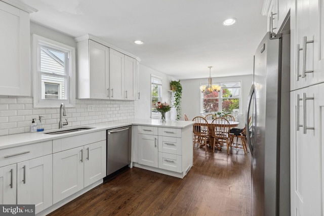 kitchen featuring stainless steel appliances, a peninsula, a sink, healthy amount of natural light, and recessed lighting