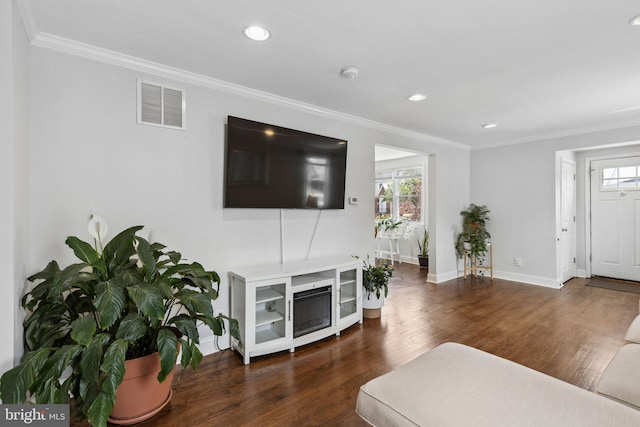 living area featuring plenty of natural light, crown molding, wood finished floors, recessed lighting, and baseboards
