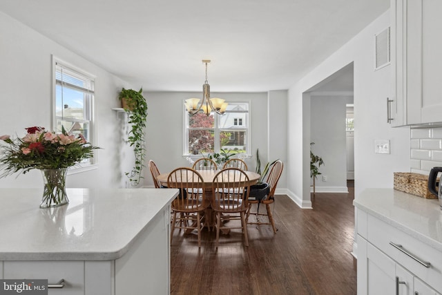 dining space featuring dark wood-style flooring, a chandelier, and baseboards