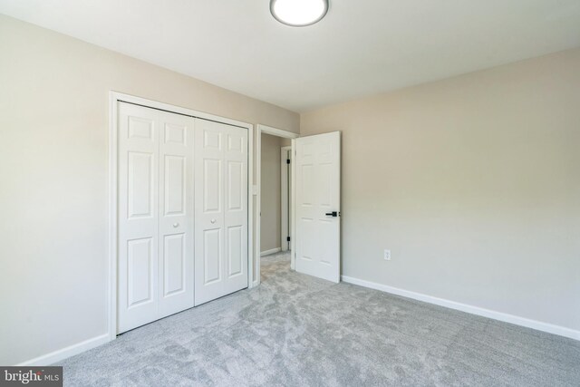 unfurnished bedroom featuring baseboards, carpet floors, and a closet