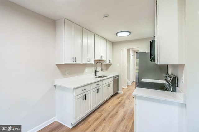 kitchen featuring a sink, stainless steel appliances, light wood-type flooring, baseboards, and light countertops