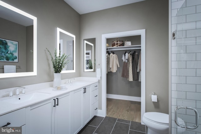 bathroom with double vanity, tile patterned flooring, toilet, and a sink