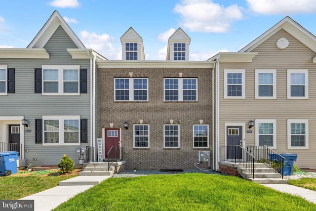 view of property featuring a front lawn and brick siding