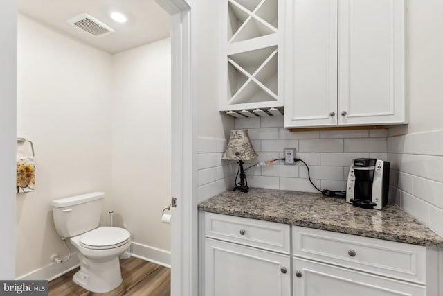 bathroom with wood finished floors, visible vents, toilet, and baseboards