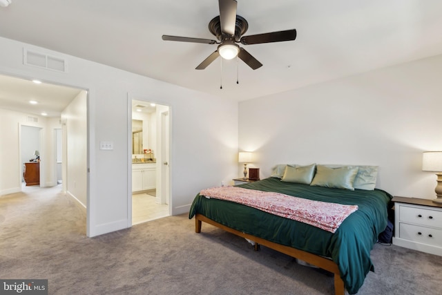 bedroom featuring light carpet, baseboards, visible vents, a ceiling fan, and ensuite bath