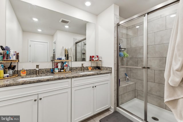 full bath with a shower stall, a sink, visible vents, and double vanity