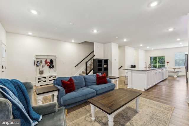 living area with recessed lighting, light wood finished floors, and stairs