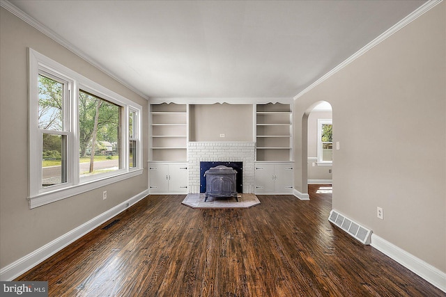 unfurnished living room featuring a wood stove, visible vents, wood finished floors, and arched walkways