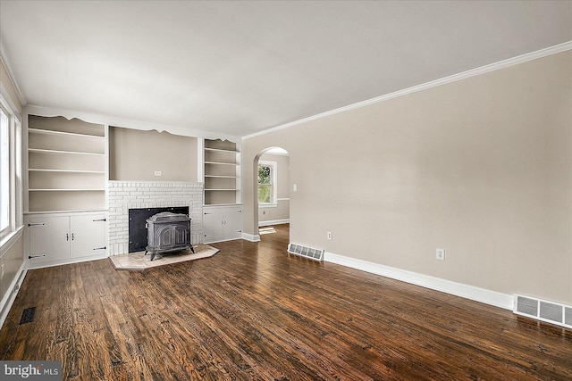 unfurnished living room with a wood stove, visible vents, and ornamental molding