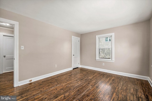 unfurnished room with baseboards and dark wood-style floors