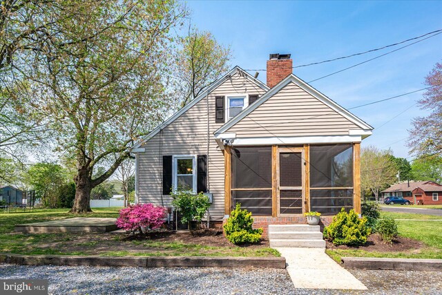 bungalow-style house with a chimney and a sunroom