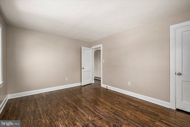 spare room featuring visible vents, baseboards, and dark wood-style floors