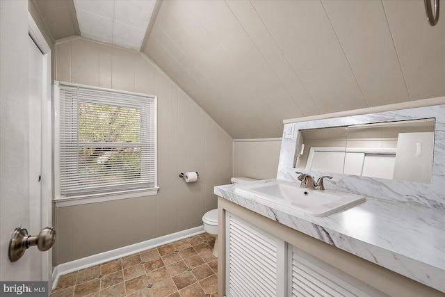 bathroom featuring vanity, toilet, baseboards, and lofted ceiling