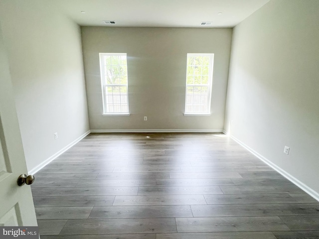 spare room with plenty of natural light, visible vents, and dark wood-type flooring