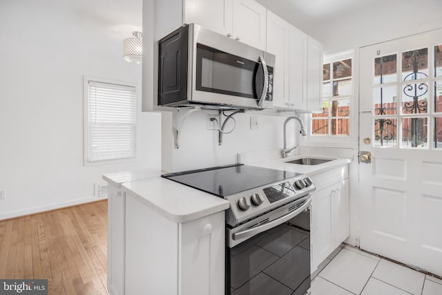 647 Emerson St NE, Washington, DC 20017 - kitchen featuring light countertops, a sink, light wood-style flooring, appliances with stainless steel finishes, and white cabinetry