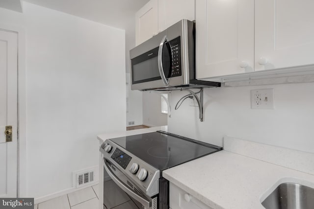 647 Emerson St NE, Washington, DC 20017 - kitchen featuring light stone countertops, visible vents, appliances with stainless steel finishes, and white cabinetry