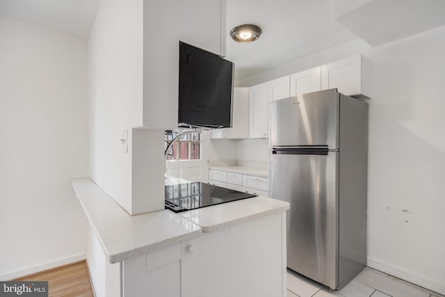 647 Emerson St NE, Washington, DC 20017 - kitchen with black electric cooktop, baseboards, freestanding refrigerator, white cabinetry, and light stone counters