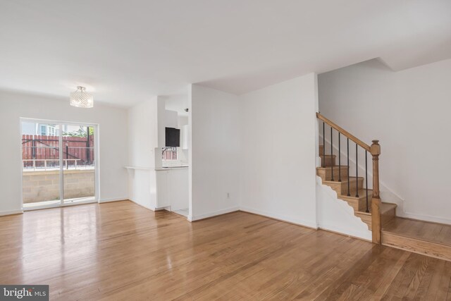 647 Emerson St NE, Washington, DC 20017 - unfurnished living room with light wood-type flooring, baseboards, and stairway