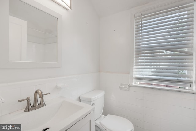 647 Emerson St NE, Washington, DC 20017 - bathroom with wainscoting, toilet, vanity, and tile walls