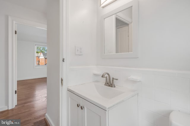 647 Emerson St NE, Washington, DC 20017 - bathroom featuring tile walls, wood finished floors, vanity, and a wainscoted wall