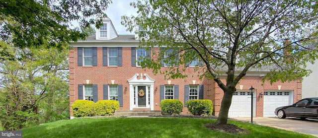 colonial inspired home with brick siding, a front lawn, and driveway