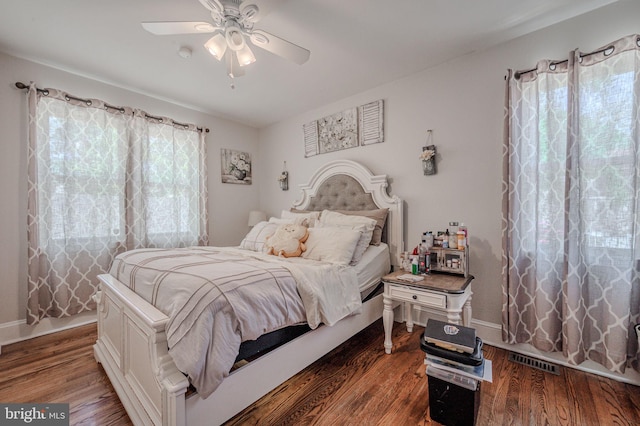 bedroom featuring a ceiling fan, baseboards, visible vents, and wood finished floors
