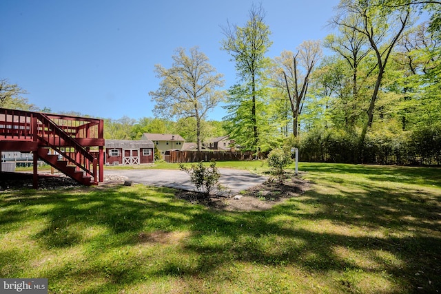 view of yard with a wooden deck, a patio area, stairway, fence, and an outdoor structure
