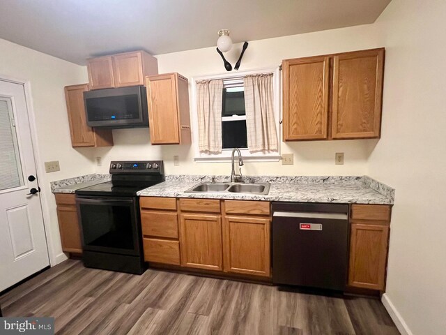 kitchen with black / electric stove, dishwasher, wood finished floors, a sink, and stainless steel microwave