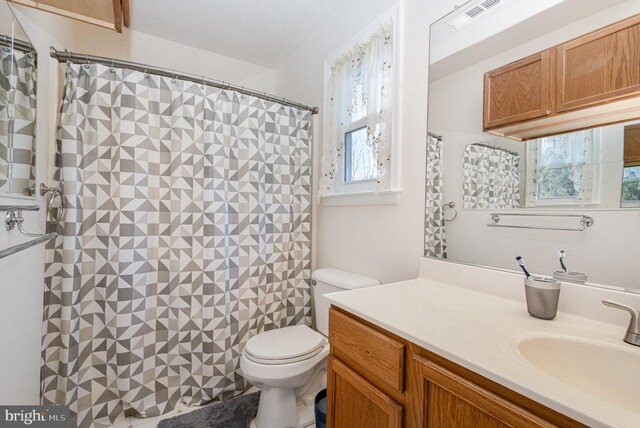 full bathroom featuring toilet, vanity, curtained shower, and visible vents