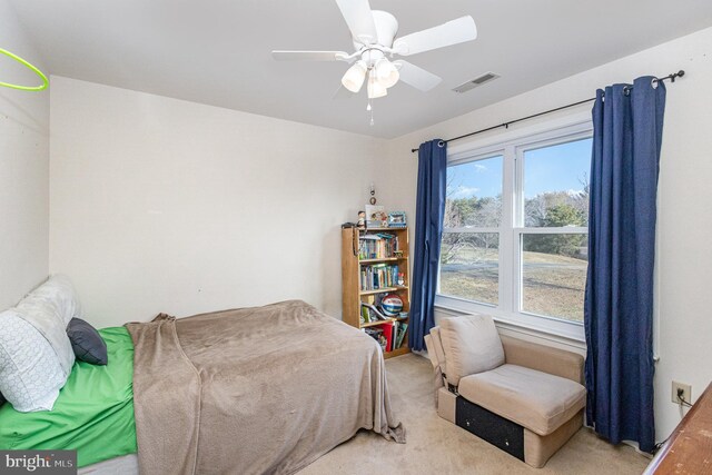 bedroom with visible vents, a ceiling fan, and light carpet