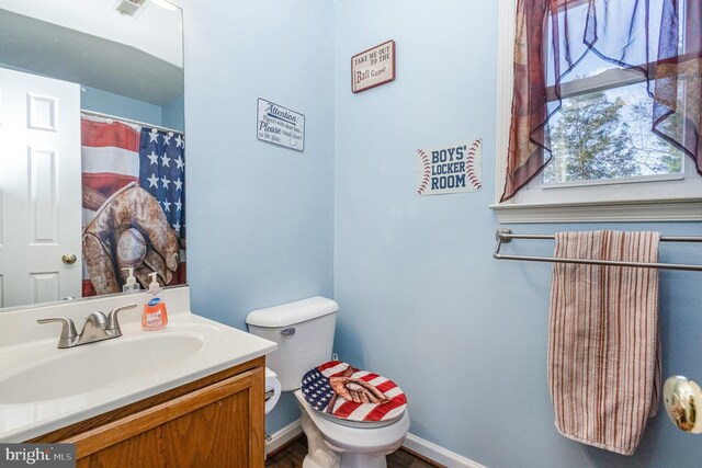 full bath with toilet, a healthy amount of sunlight, vanity, and baseboards