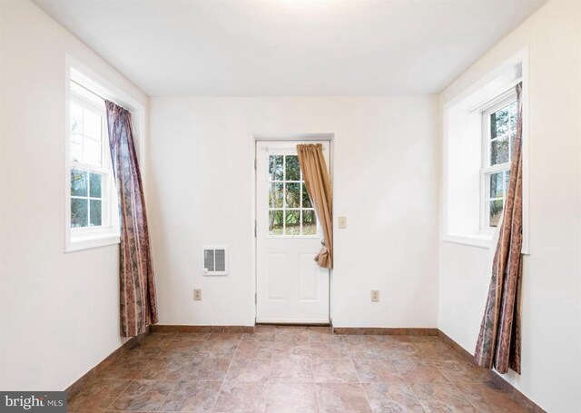 empty room featuring baseboards, a healthy amount of sunlight, and stone finish floor