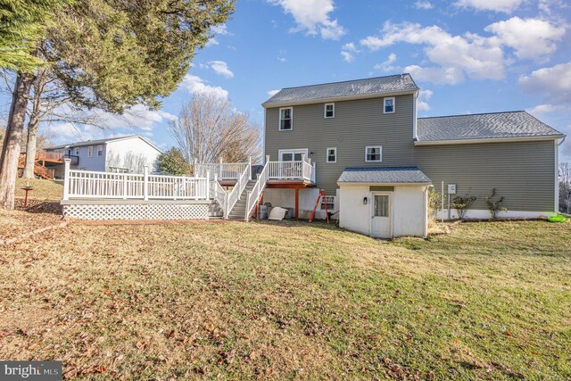 rear view of property with stairway, a wooden deck, and a lawn