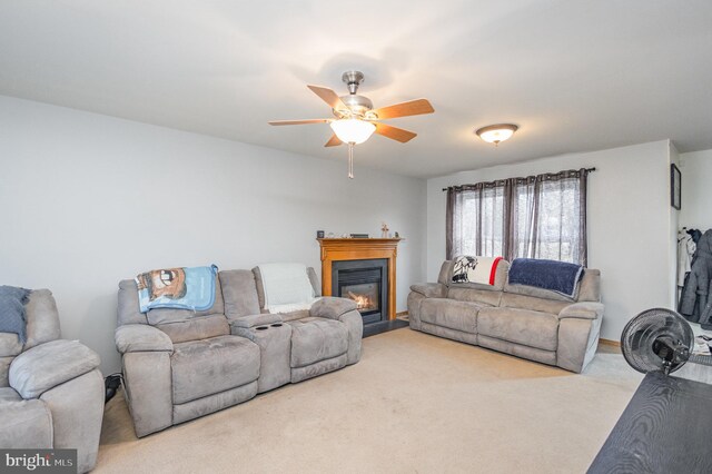 living area featuring a glass covered fireplace, carpet floors, and a ceiling fan