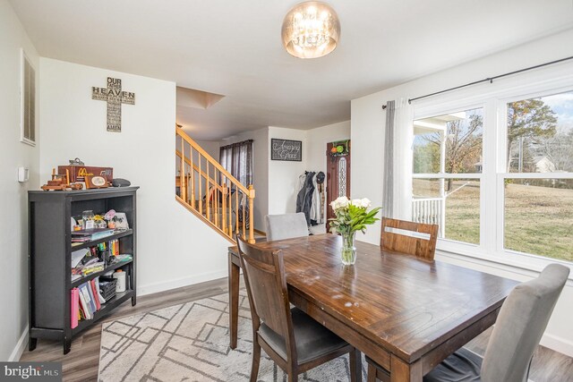 dining area with wood finished floors, baseboards, and stairway