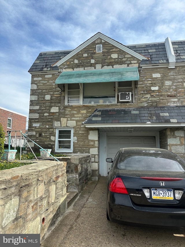 view of front of property featuring stone siding, a high end roof, cooling unit, and a garage